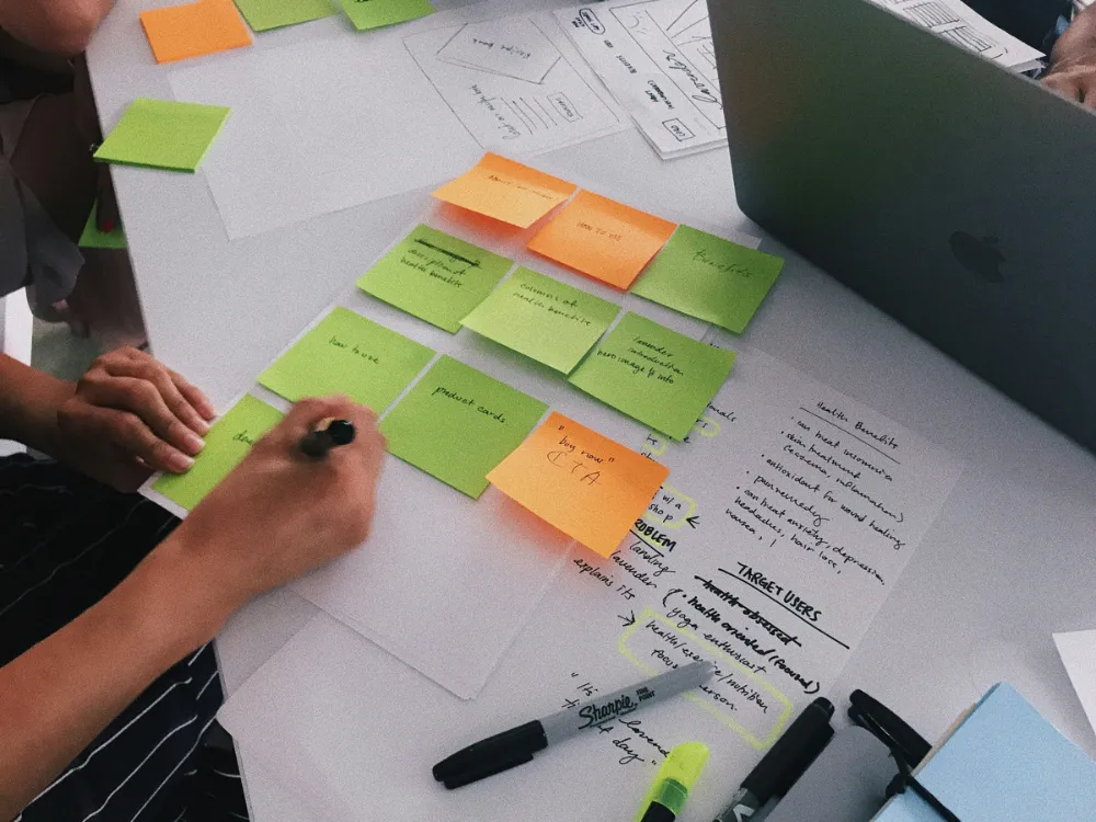 Person skriver p&aring; post-it-lappar vid dator