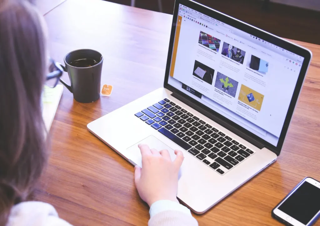 Person anv&auml;nder laptop vid bordet.